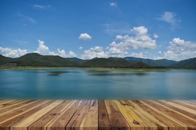 Tabela de madeira vazia de perspectiva no topo ao longo da barragem e montanha com céu azul no fundo