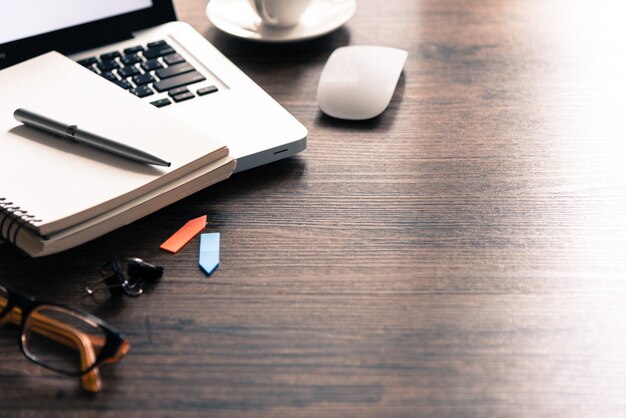 Tabela de mesa de escritório com computador, óculos, mouse branco, caneta prata e xícara de café preto