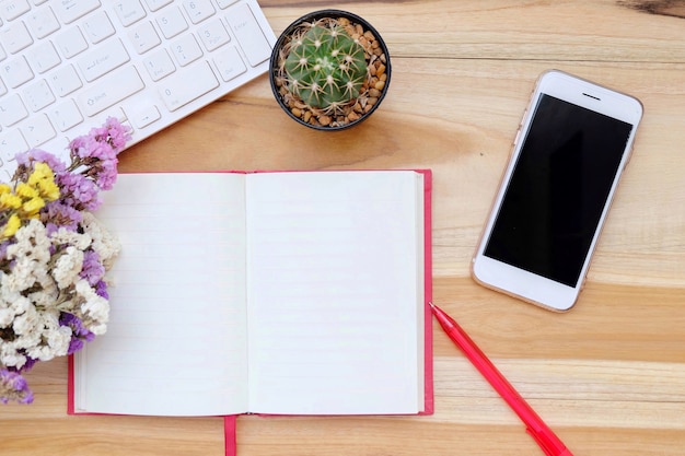 Foto tabela de mesa de escritório com teclado, caderno, caneta e flor buquê seco.