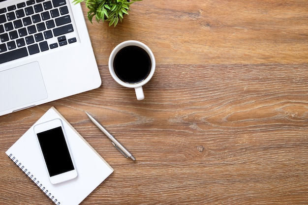 Tabela de mesa de escritório de madeira com smartphone, computador portátil e suprimentos.