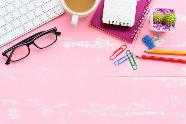 Tabela do escritório com acessórios do espaço de trabalho e do escritório no fundo de madeira cor-de-rosa.