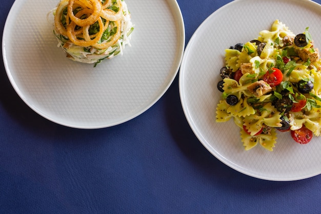 Tabelle mit Draufsicht vieler Salate. Verschiedene Salate auf Betontisch, Ansicht von oben. Gemüsesalat, Salat mit Räucherlachs, Ceviche und Stracciatella.