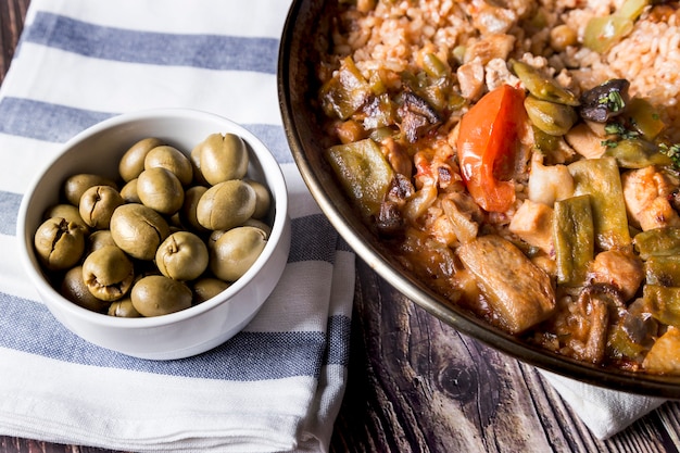 Tabelle mit grünen Oliven und vegetarischer Paella Gesundes Essen mit Gemüse und Oliven. Mediterranes Essen.