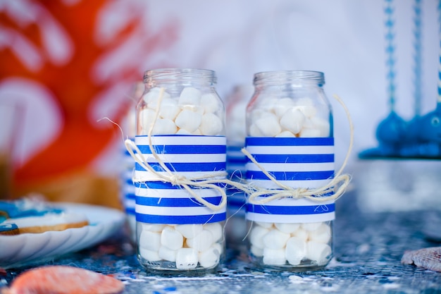 Tabelle mit Seedekor und Platte mit Bonbons, Süßigkeiten, Plätzchen und verziert Gläser mit Eibisch