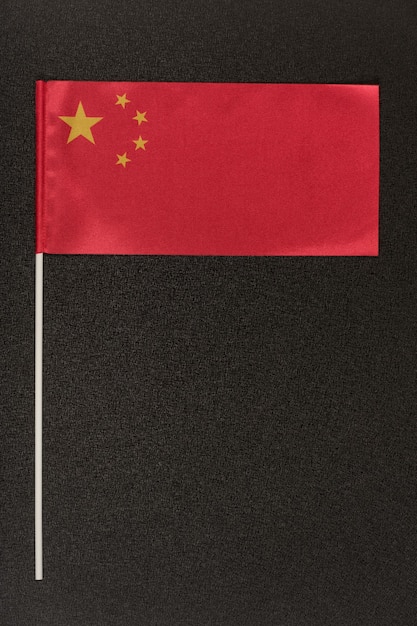 Tabellenflagge von China auf schwarzem Hintergrund. Rote Fahne mit Sternen. Vertikaler Rahmen.