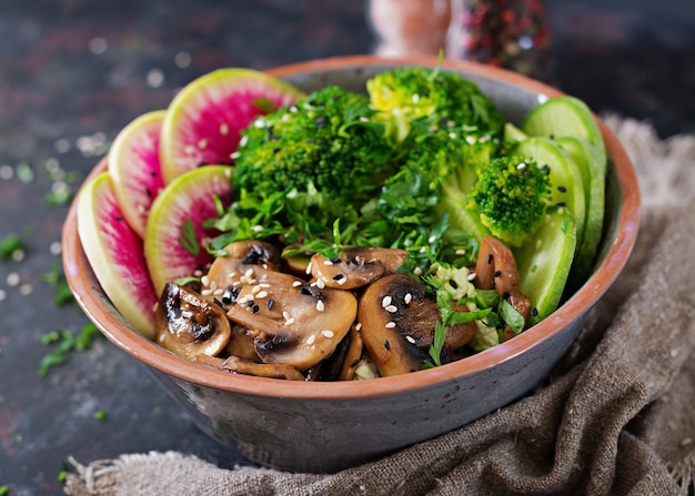 Tabla de la comida de la cena del cuenco de Buda del vegano Champiñones a la plancha, brócoli, ensalada de rábanos.