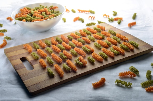 Tabla cortada de bambú con pasta vegetal de color naranja y verde sobre un mantel de lino blanco