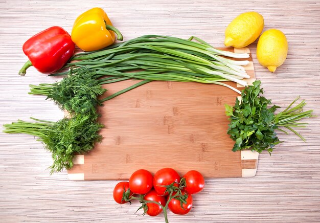 Tabla de cortar de cocina con verduras, un tomate y un limón.