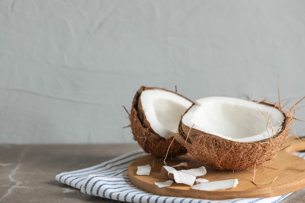 Tabla de cortar con coco partido en la mesa contra gris