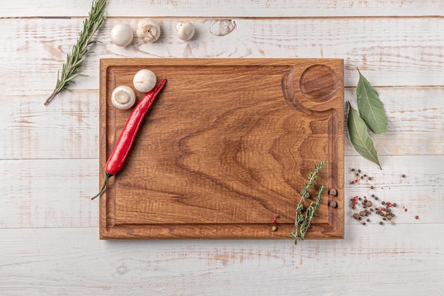 Tabla de cortar cuadrada de madera de color oscuro con bordes de champiñones, chile y especias en una maqueta de fondo blanco con espacio de copia para la vista superior del texto