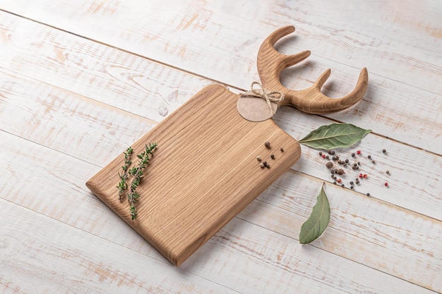 Tabla de cortar cuadrada de madera con cuernos en forma de asa y especias en una maqueta de fondo blanco con espacio de copia para la vista lateral del texto