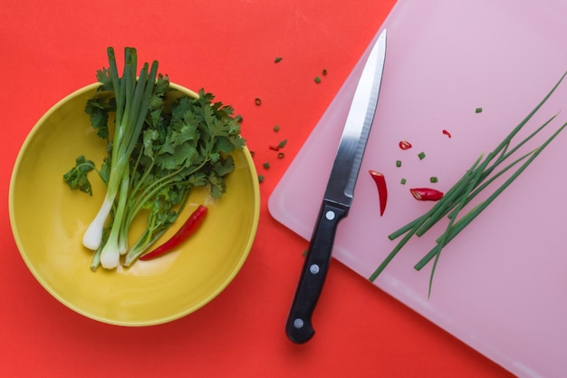 Una tabla de cortar con un cuchillo junto a una tabla de cortar con verduras picadas.