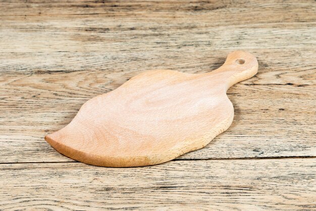 La tabla de cortar en forma de hoja se encuentra encima de una vieja mesa de madera