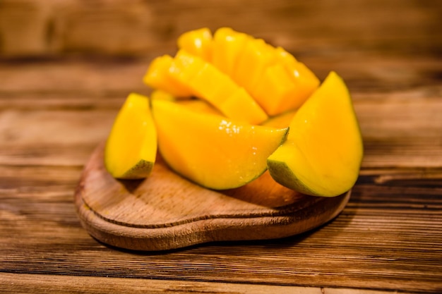 Tabla de cortar con fruta de mango picada en mesa de madera rústica