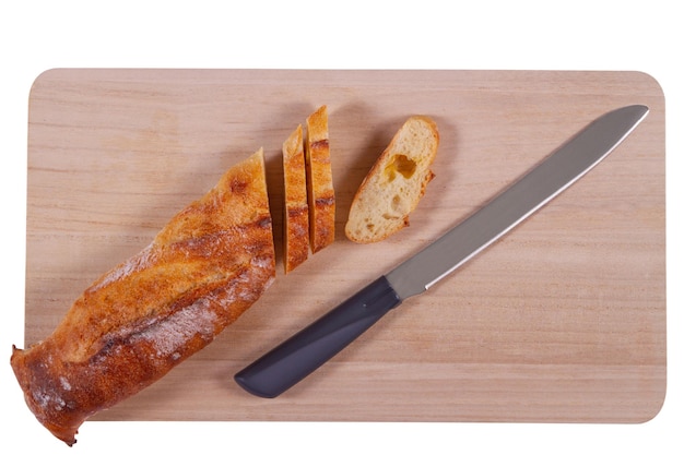 Tabla de cortar de madera con baguette en rodajas y cuchillo aislado sobre fondo blanco.