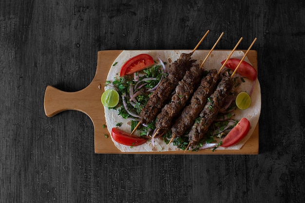 Foto una tabla de cortar de madera con brochetas de carne y verduras.