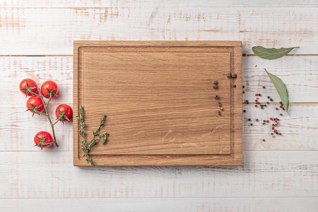 Tabla de cortar de madera cuadrada con tomates cherry y especias en una maqueta de fondo blanco con espacio de copia para la vista superior del texto