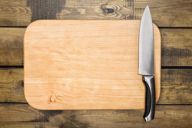 Tabla de cortar de madera y cuchillo en el fondo