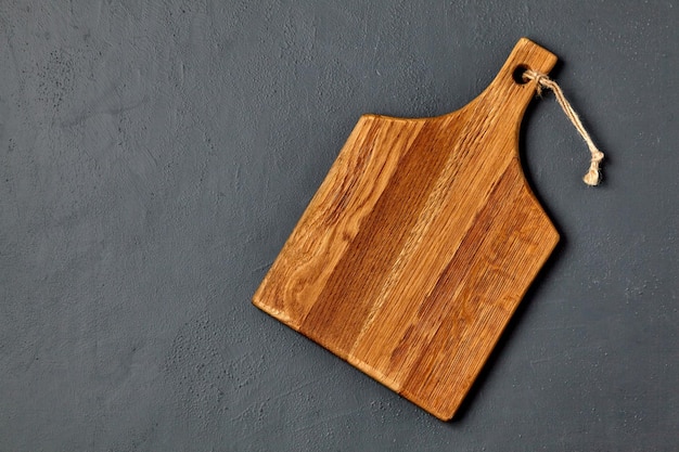 Tabla de cortar de madera marrón sobre una mesa de hormigón oscuro Plantilla para colocar los platos Vista superior con espacio de copia Plano