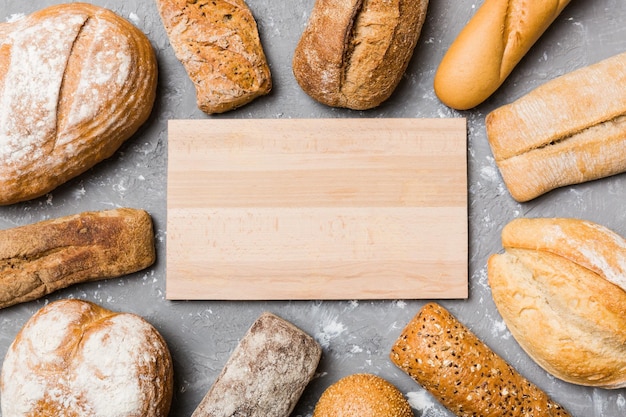 Tabla de cortar de madera minimalista maqueta en blanco sobre el fondo de Tipos de pan casero Diferentes tipos de pan fresco como vista superior de fondo con espacio para su texto o diseño