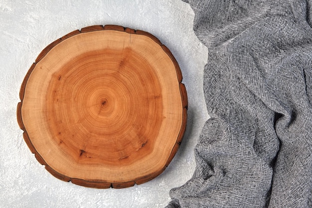 Tabla de cortar de madera o posavasos y paño de cocina gris sobre una mesa de hormigón gris claro