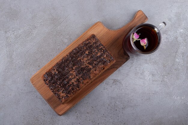 Una tabla de cortar de madera de pastel de chocolate y una taza de té.