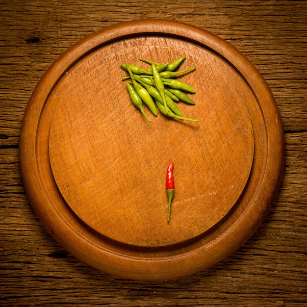 Foto tabla de cortar de madera redonda. chiles verdes y rojos