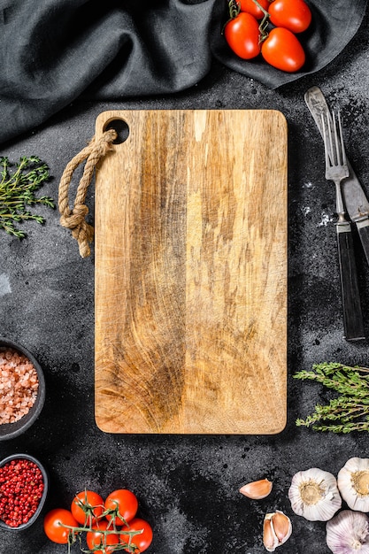 Tabla de cortar de madera rodeada de verduras y especias