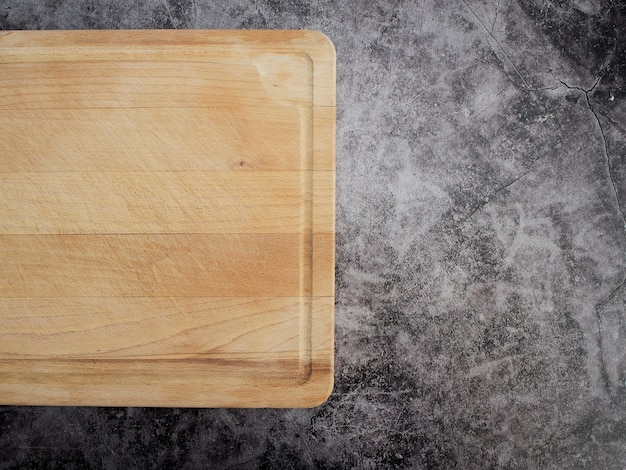 Foto tabla de cortar madera sobre mesa de mármol gris.