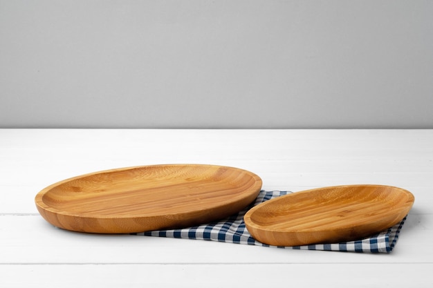 Tabla de cortar de madera sobre una servilleta de algodón sobre una mesa de madera blanca