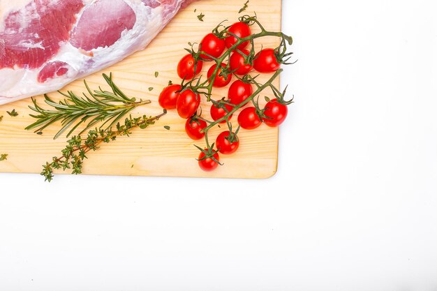 Una tabla de cortar con un montón de tomates y romero.