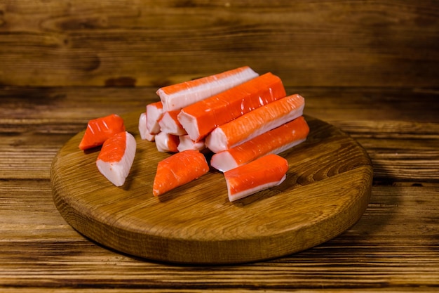 Tabla de cortar con montones de palitos de cangrejo en una mesa de madera