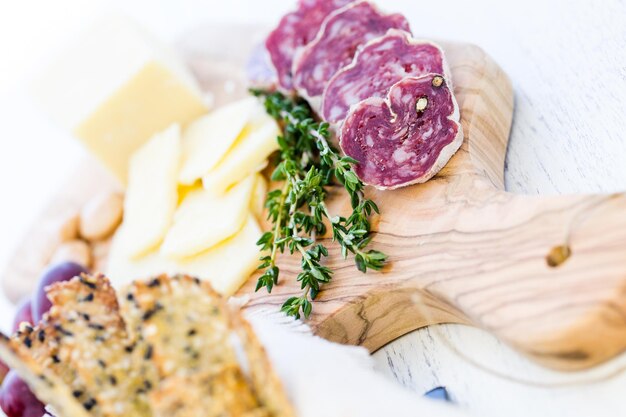 Tabla de cortar pequeña con bocadillos de queso y salami.