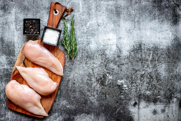 Una tabla para cortar con pollo crudo y sal