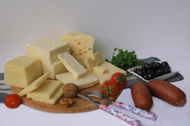 Una tabla de cortar con queso y un cuchillo con un tenedor y un cuchillo con un bol pequeño de perejil.