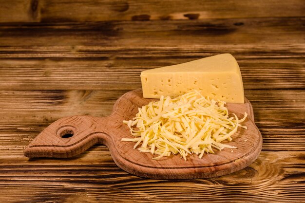 Tabla de cortar con queso rallado sobre mesa de madera rústica