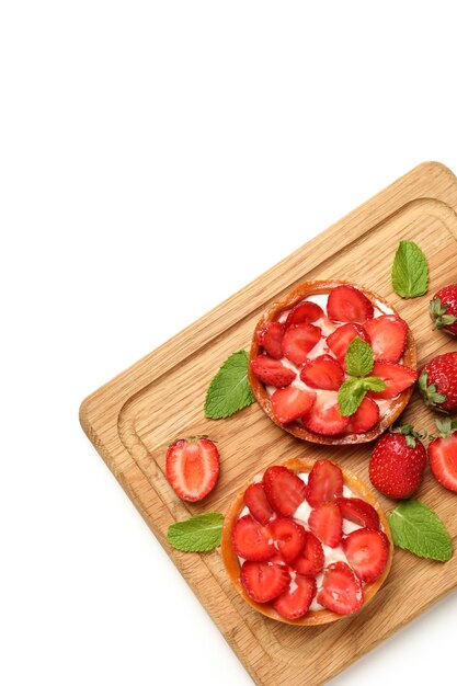 Foto tabla de cortar con tartas de fresa sobre fondo blanco.