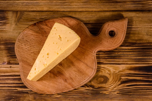 Tabla de cortar con trozo de queso en la mesa de madera Vista superior