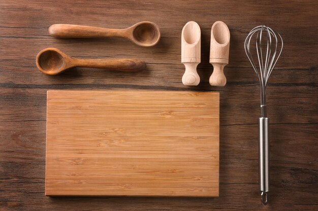Tabla de cortar y utensilios de cocina sobre fondo de madera Clases magistrales de cocina