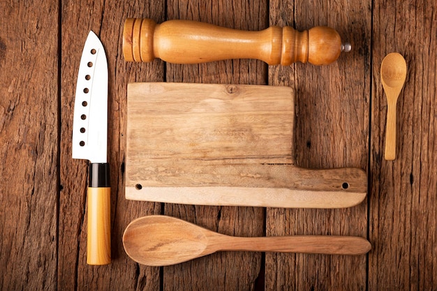 Tabla de cortar con utensilios de cocina sobre fondo rústico.