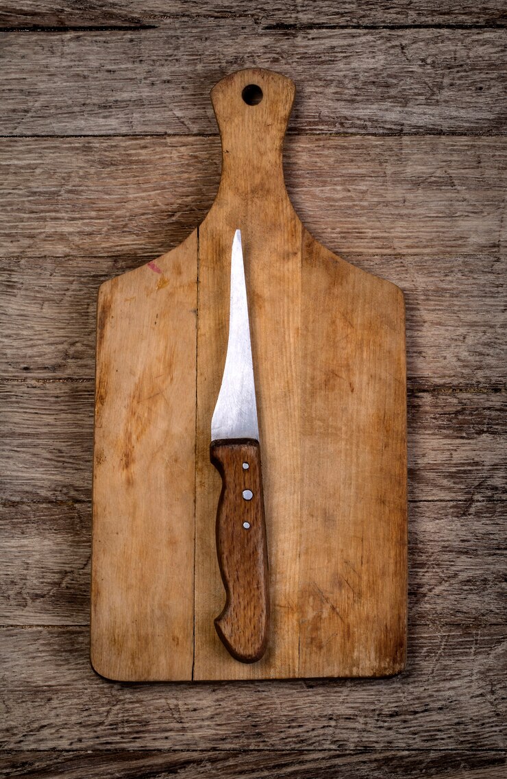 Foto tabla de cortar vacía con un cuchillo sobre una mesa de madera de grunge angustiado