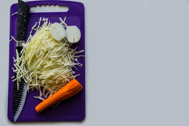 En la tabla de cortar verduras con un cuchillo sobre un fondo blanco.