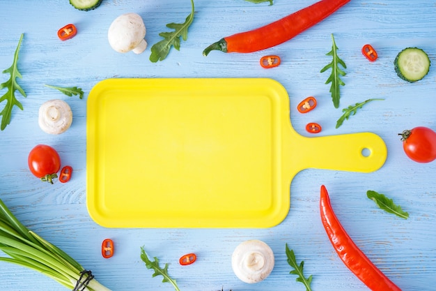 Tabla de cortar y verduras en la mesa de madera, lugar para el texto, vista superior.