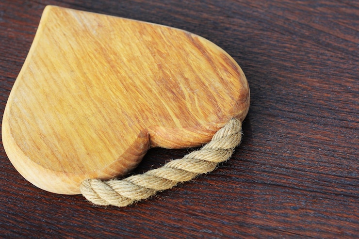 Foto tabla de corte en forma de corazón sobre un fondo de madera rústica