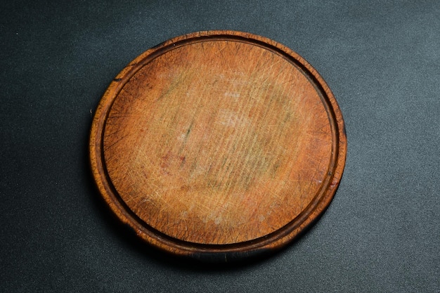 Tabla de corte redonda de cocina Tabla marrón Utensilios de cocina sobre un fondo oscuro