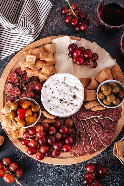 Foto tabla de embutidos mediterráneos con varios tipos de aperitivos para compartir en la vista superior de fondo de hormigón
