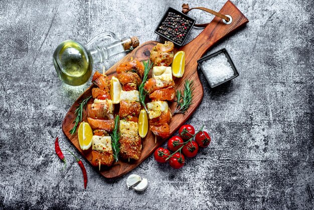 Una tabla de madera con brochetas de pescado y una copa de vino blanco.