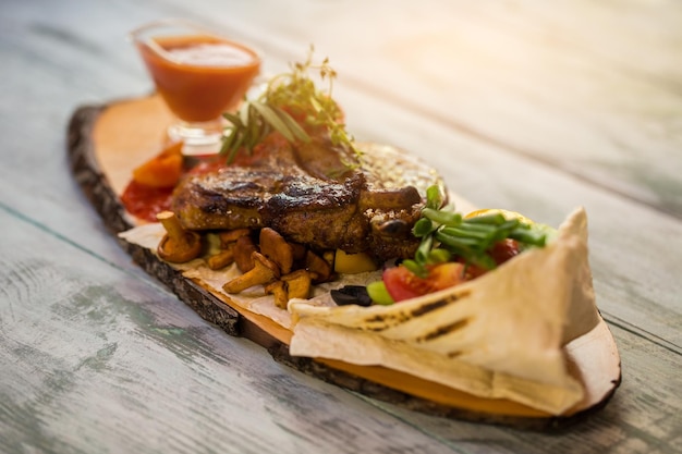 Tabla de madera con carne cocida. Pan pita y verduras. Receta de plato con carne de cerdo. El sabor es inolvidable.