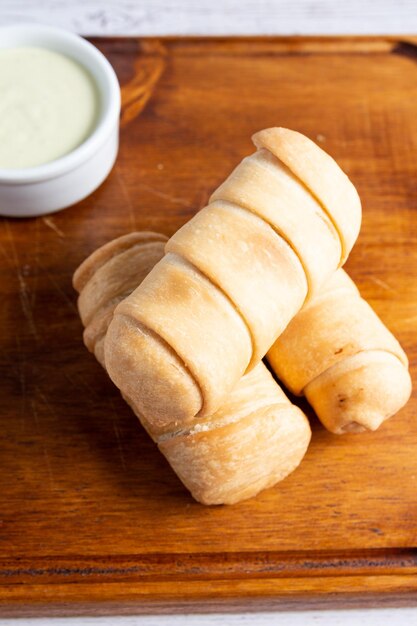 Una tabla de madera con cuatro rollos de pan, uno de los cuales está etiquetado como "vegano".