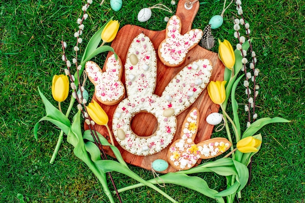 Una tabla de madera con galletas de Pascua y flores.